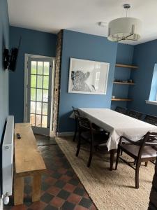 a dining room with a table and blue walls at Apple Cottage in Newton Stewart