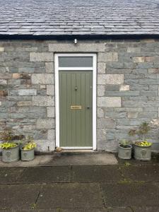 una porta verde in una casa di mattoni con piante in vaso di Apple Cottage a Newton Stewart