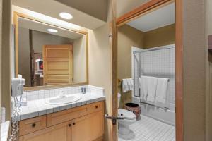 a bathroom with a sink and a toilet and a mirror at Palisades Tahoe Lodge Rentals Two Bedroom #804 in Olympic Valley +9 photos