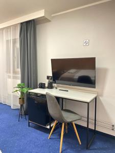 a desk with a chair and a television on a wall at Garbarska 22 Aparthotel in Krakow