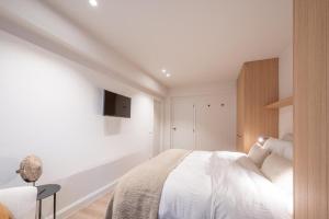 een witte slaapkamer met een bed en een tv aan de muur bij Girasol in Knokke-Heist