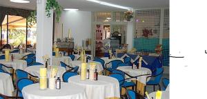 Habitación con mesas blancas y sillas azules. en Hotel Anfora, en Capoliveri