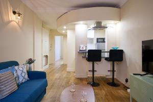 sala de estar con sofá azul y cocina en Le Refuge Parisien, en Montrouge