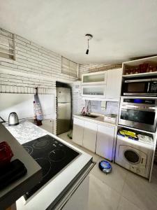 cocina con armarios blancos y fogones en Apartamento en Carrasco Sur, cerca del aeropuerto y la rambla, en Montevideo