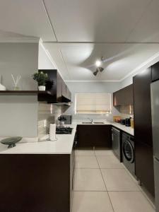 een keuken met zwart-witte kasten en een wastafel bij Apartment in Kyalami/Midrand. in Midrand