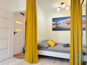 a bed with yellow curtains in a room at Honey Apartment in Gdańsk