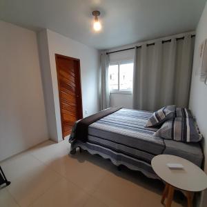 a bedroom with a bed with a table and a window at FLAT a 2min do relogio da flores com ar condicionado in Garanhuns +24 photos
