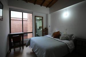 a bedroom with a bed and a desk and a window at Apartamento Cómodo en el Poblado in Medellín