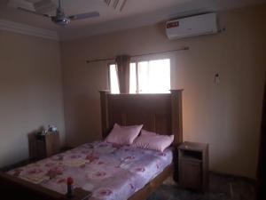 Schlafzimmer mit einem Bett mit rosa Kissen und einem Fenster in der Unterkunft 3 bedrooms first story apartment in Sukuta