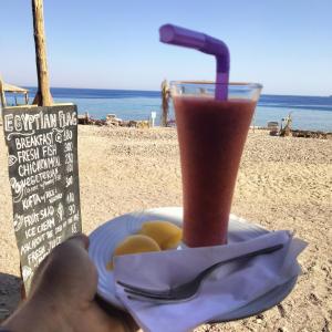 una persona sosteniendo un plato con una bebida en la playa en Abou Saif-Egyptian flag, en Dahab