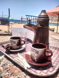 dos tazas de café sentadas en una mesa cerca de la playa en Abou Saif-Egyptian flag, en Dahab
