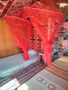 Una cama con cortinas rojas encima. en Abou Saif-Egyptian flag, en Dahab