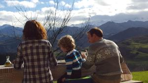 Dos adultos y un niño sentado en una mesa con vistas a las montañas en Heredad de la Cueste, en Llenín