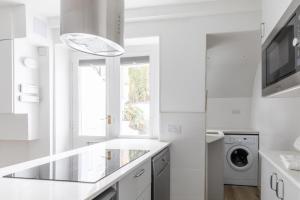 a white kitchen with a washer and dryer at Sleek & Well-Connected Studio Flat Archway! in London