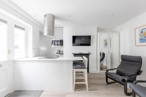 a white kitchen with a sink and a chair at Sleek & Well-Connected Studio Flat Archway! in London