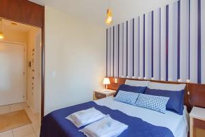 um quarto com uma cama com almofadas azuis e brancas em Estúdio Próximo a Beira Mar em Florianópolis