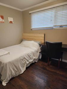 een slaapkamer met een bed, een bureau en een stoel bij Like Home in Regina