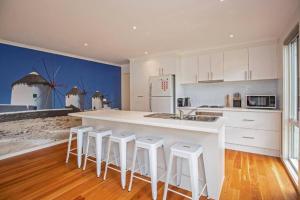 a kitchen with a large white island with stools at Bay Breeze Retreat in Cowes