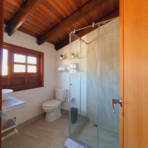 a bathroom with a toilet and a glass shower at La Huerta Hotel Boutique in Tibasosa