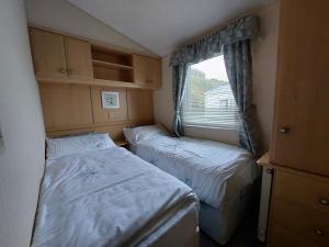 - 2 lits dans une petite chambre avec fenêtre dans l'établissement Winnie - Caravan mit Meerblick, à Drummore