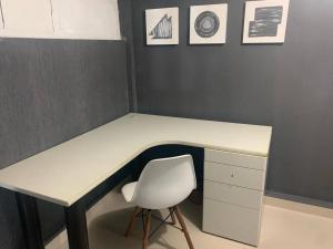 einen Schreibtisch mit einem weißen Stuhl und einen Schreibtisch mit einem weißen Stuhl in der Unterkunft Loft Eco City 02-Espaçoso e Confortável c/ Garagem in Curitiba