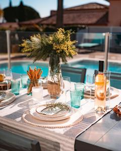 ein Tisch für eine Mahlzeit mit einer Blumenvase in der Unterkunft Magnifique Villa Piscine Pergola Proche Mer in Carqueiranne