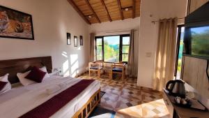 1 dormitorio con cama, mesa y ventana en Corbett Mid Forest House en Rāmnagar
