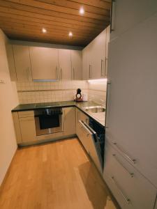 a kitchen with white cabinets and a wooden floor at Appartement in St. Niklaus in Sankt Niklaus