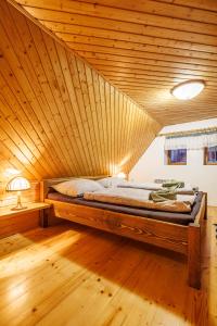 a bed in a room with a wooden ceiling at Chaloupka u Káji in Vítkovice