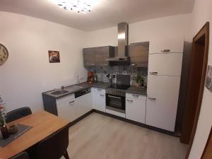 a kitchen with white appliances and a wooden table at Ferienwohnung Christina in Möllbrücke +6 photos