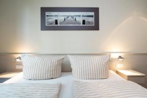 a bed with two pillows and a picture on the wall at Sölring Lek Westerland in Westerland (Sylt)