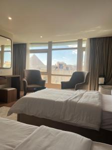 开罗The Home Boutique Hotel Pyramids Inn的酒店客房,配有两张床和两把椅子