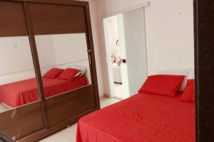um quarto com um espelho e uma cama vermelha em Casa Ventos Guaibim em Guaibim