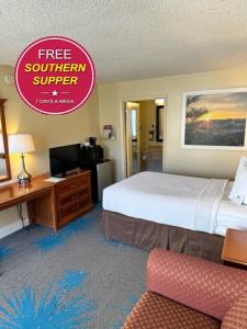 a hotel room with a bed and a desk with a television at Days Inn by Wyndham Asheville West in Candler