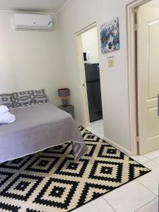 a bedroom with a bed and a black and white rug at 1 Bed Cottage in Gated Community in Banks