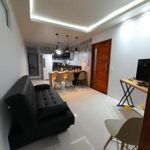 ein Wohnzimmer mit einem schwarzen Sofa und einer Küche in der Unterkunft FLAT a 2min do relogio da flores com ar condicionado in Garanhuns