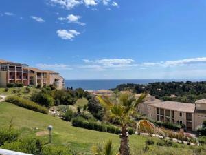 a view of a resort with a palm tree and the ocean at CAP ESTEREL, T2 VUE MER 4 couchages adapté PMR in Saint-Raphaël