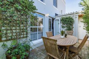 un patio con mesa de madera y sillas en Cosy New Home in Claremont en Ciudad del Cabo