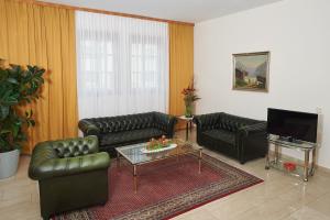 a living room with leather couches and a coffee table at Pension Sprinzl in Schwechat