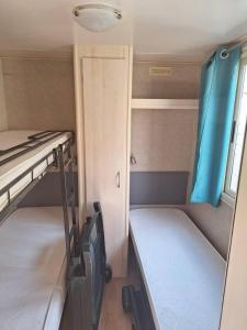 Habitación pequeña con 2 literas y puerta en Comfortable campsite-chalet G14 Tuscany near sea, en Viareggio