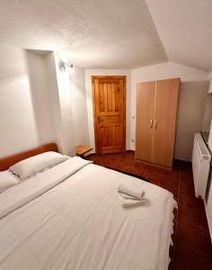 a bedroom with a large white bed and a wooden cabinet at Apartmani Ivan in Kupres