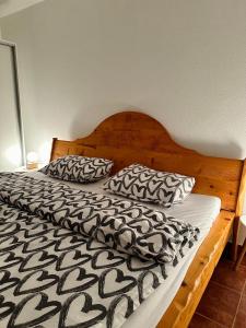 a bed with a black and white comforter and pillows at Apartmani Ivan in Kupres