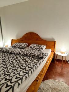 1 dormitorio con cama de madera y edredón blanco y negro en Apartmani Ivan en Kupres