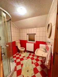a red and white bathroom with a toilet and a sink at Apartmani Ivan in Kupres