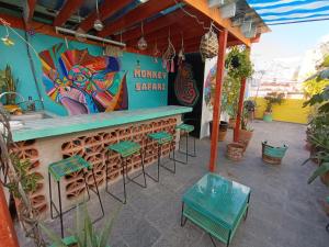 un bar con sgabelli verdi e un dipinto sul muro di Monkey Safari Hostel a Querétaro