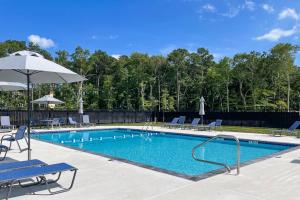 einen Pool mit Stühlen und einem Sonnenschirm in der Unterkunft Sea Oaks Village 5 in Berlin