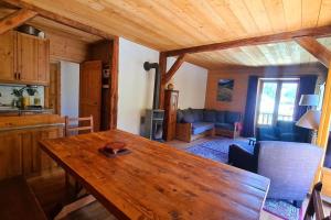 a dining room with a wooden table and a living room at Appartement de charme, vue sur les montagnes. in Aiguilles