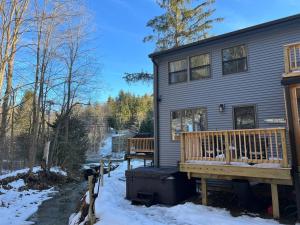 ein Haus mit einer Holzterrasse im Schnee in der Unterkunft SKI Bike, Hike & Golf Townhouse w/ Hot tub in Ellicottville