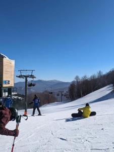 a group of people sitting in the snow on a ski slope at Chalet 86 - 3 Minutes From Whiteface Mountain in Wilmington