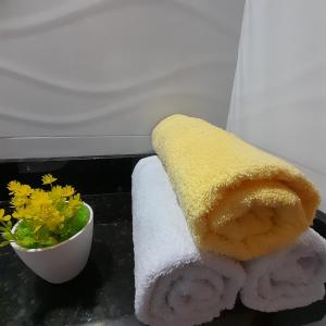 a couple of towels and a bowl of flowers at FLAT a 2min do relogio da flores com ar condicionado in Garanhuns
